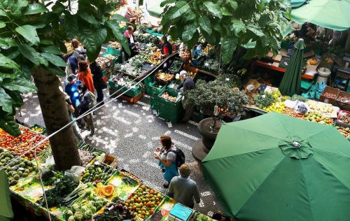 Local market with people walking through fresh fruit and vegetable stalls